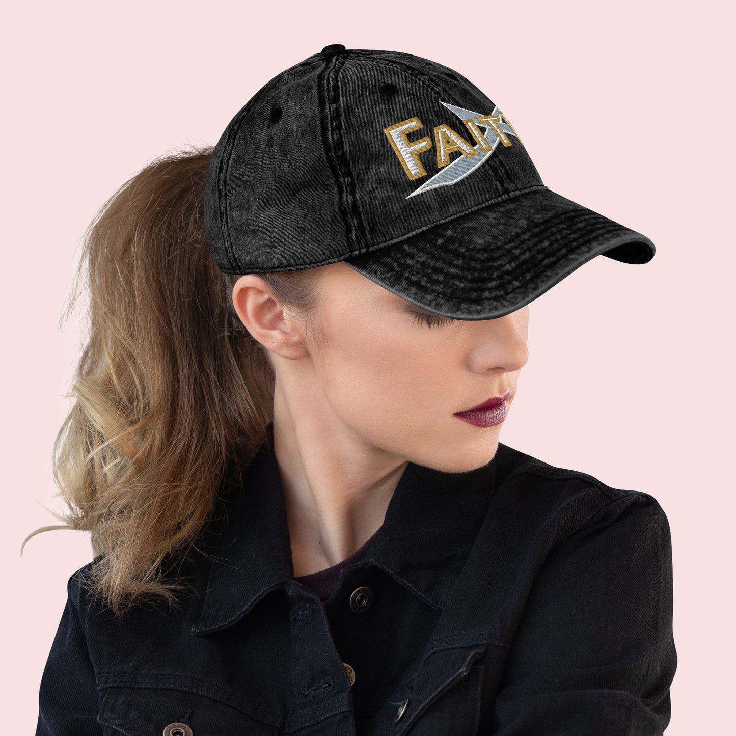Side view of female wearing a black cap with 'FAITH' embroidery on a pink background