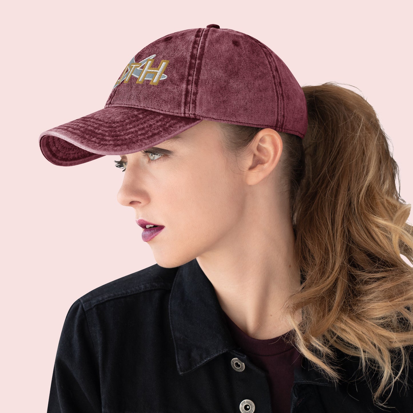 Side view of female wearing a maroon cap with 'FAITH' embroidery on a pink background