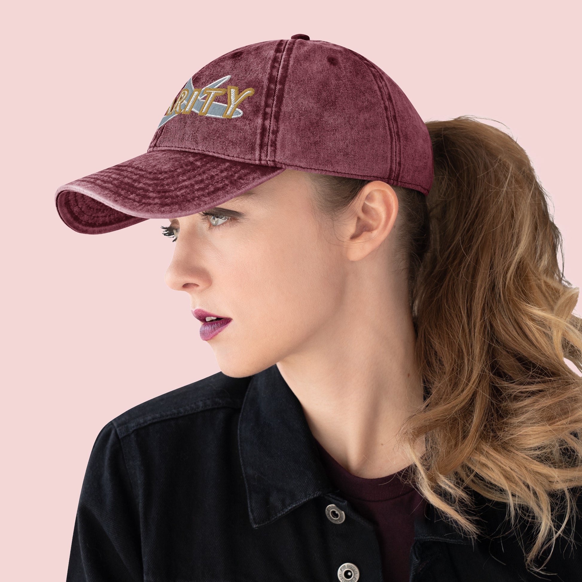 Side view of female wearing a maroon cap with 'Charity' text on a pink background