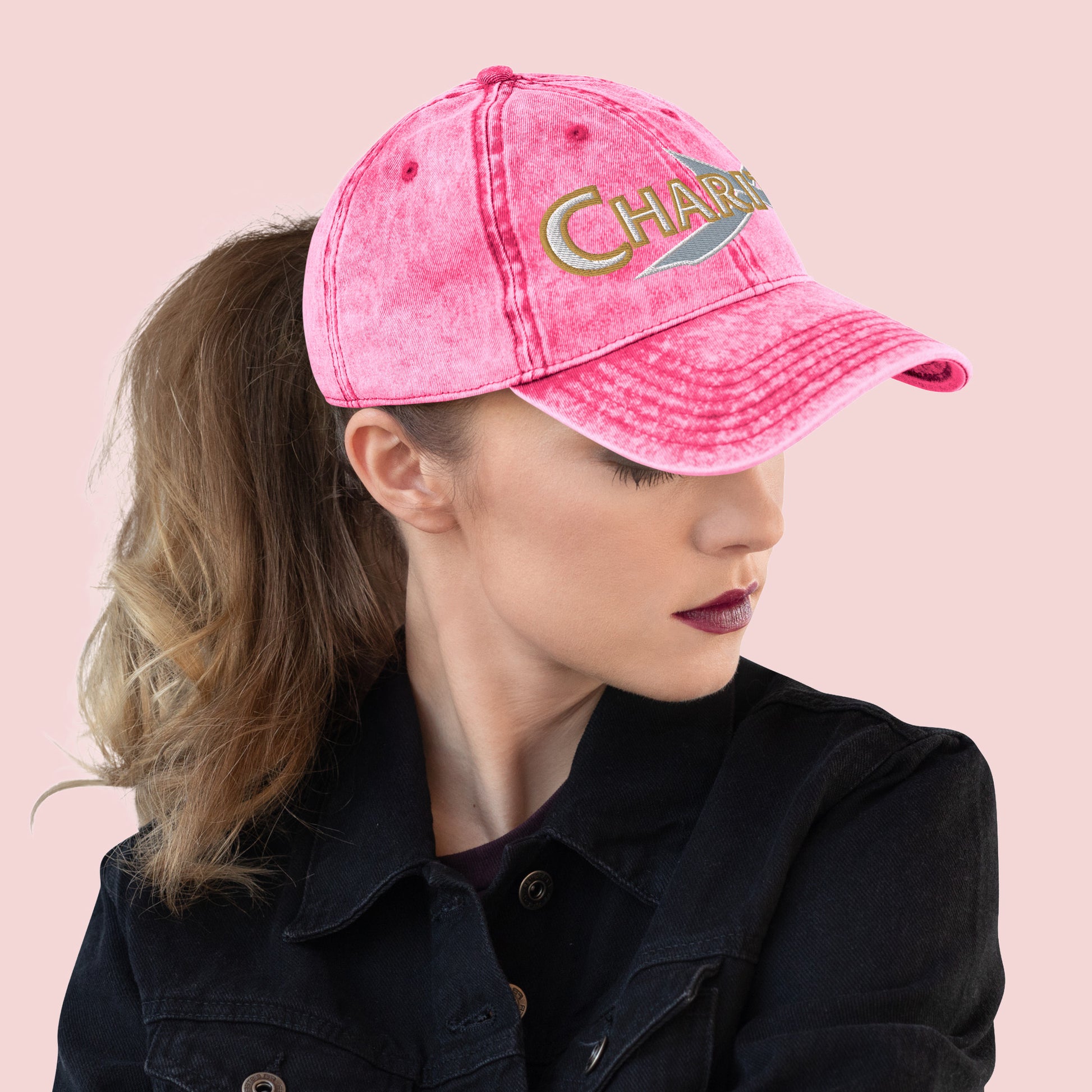 Side view of female wearing a pink cap with 'Charity' text on a pink background