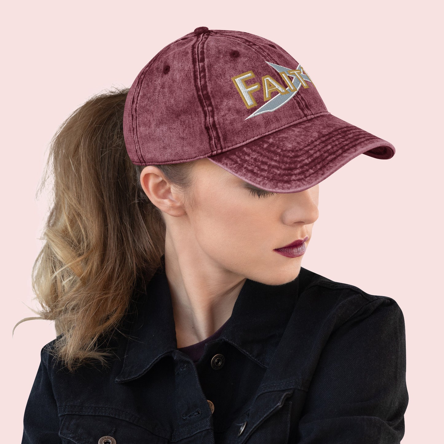 Side view of female wearing a maroon cap with 'FAITH' embroidery on a pink background