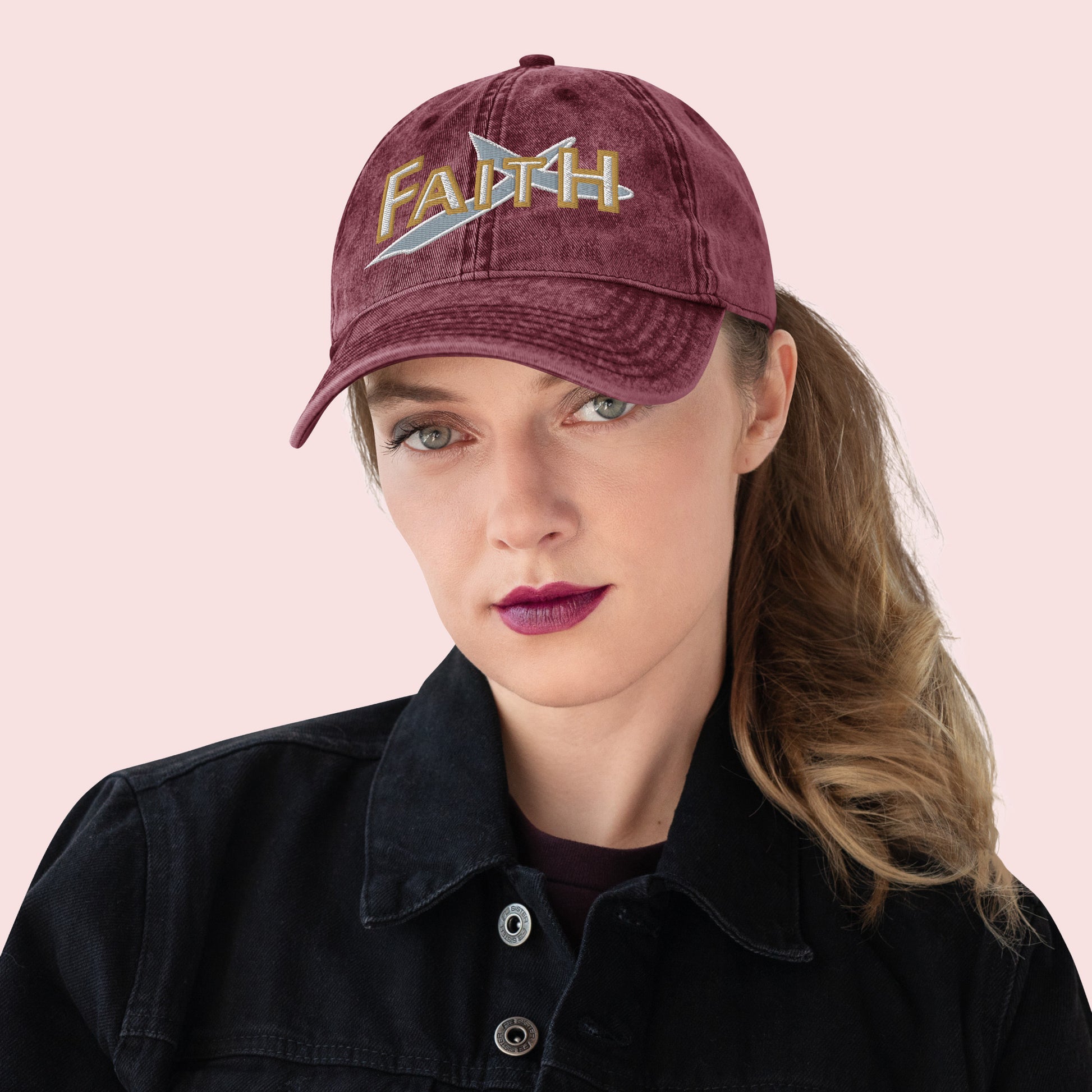 Female wearing a maroon cap with 'FAITH' embroidery on a pink background
