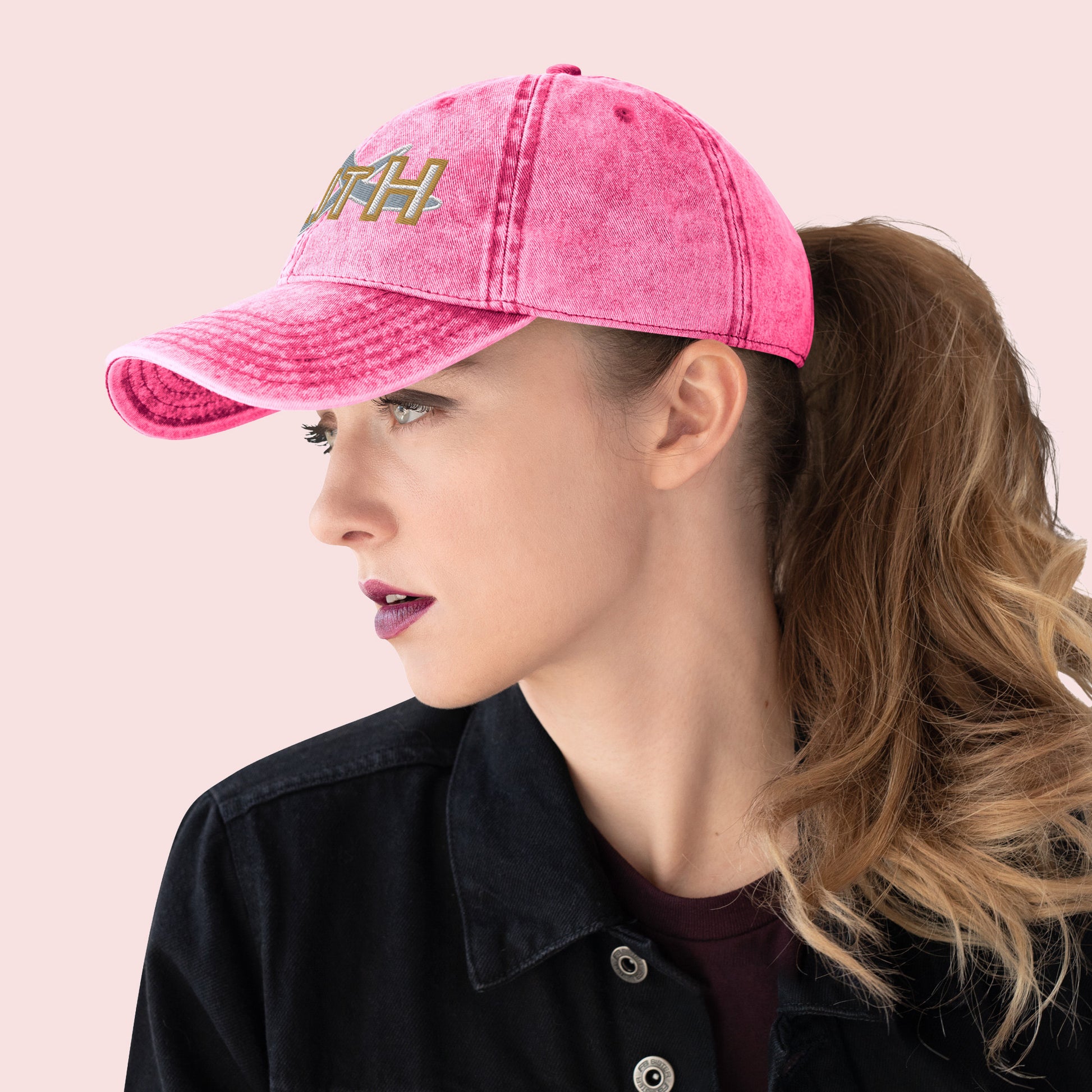 Side view of female wearing a pink cap with 'FAITH' text on a light pink background