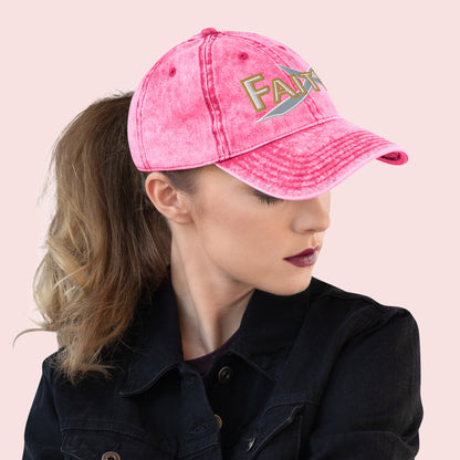 Side view of female wearing a pink cap with 'FAITH' text on a light pink background