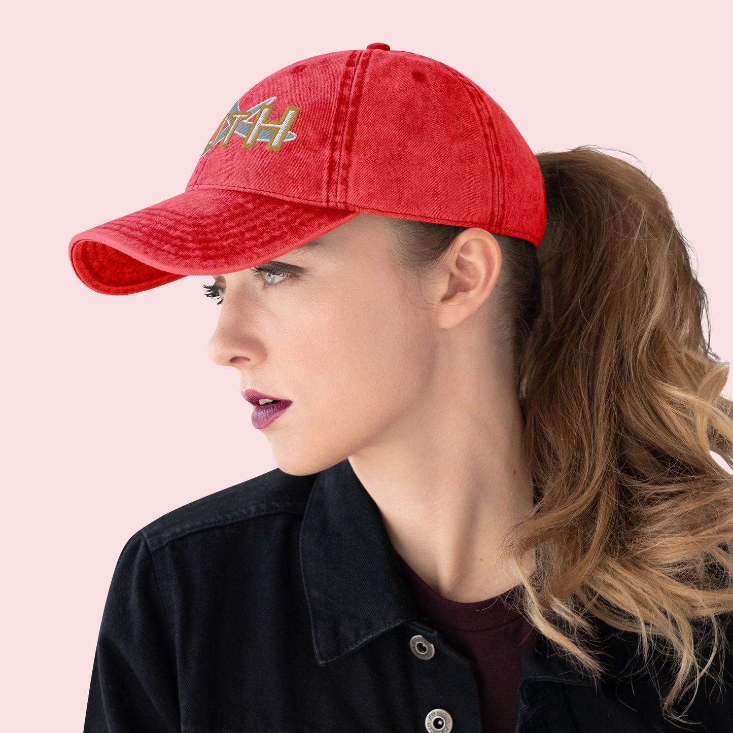 Side view of female wearing a red cap with 'FAITH' text on a light pink background