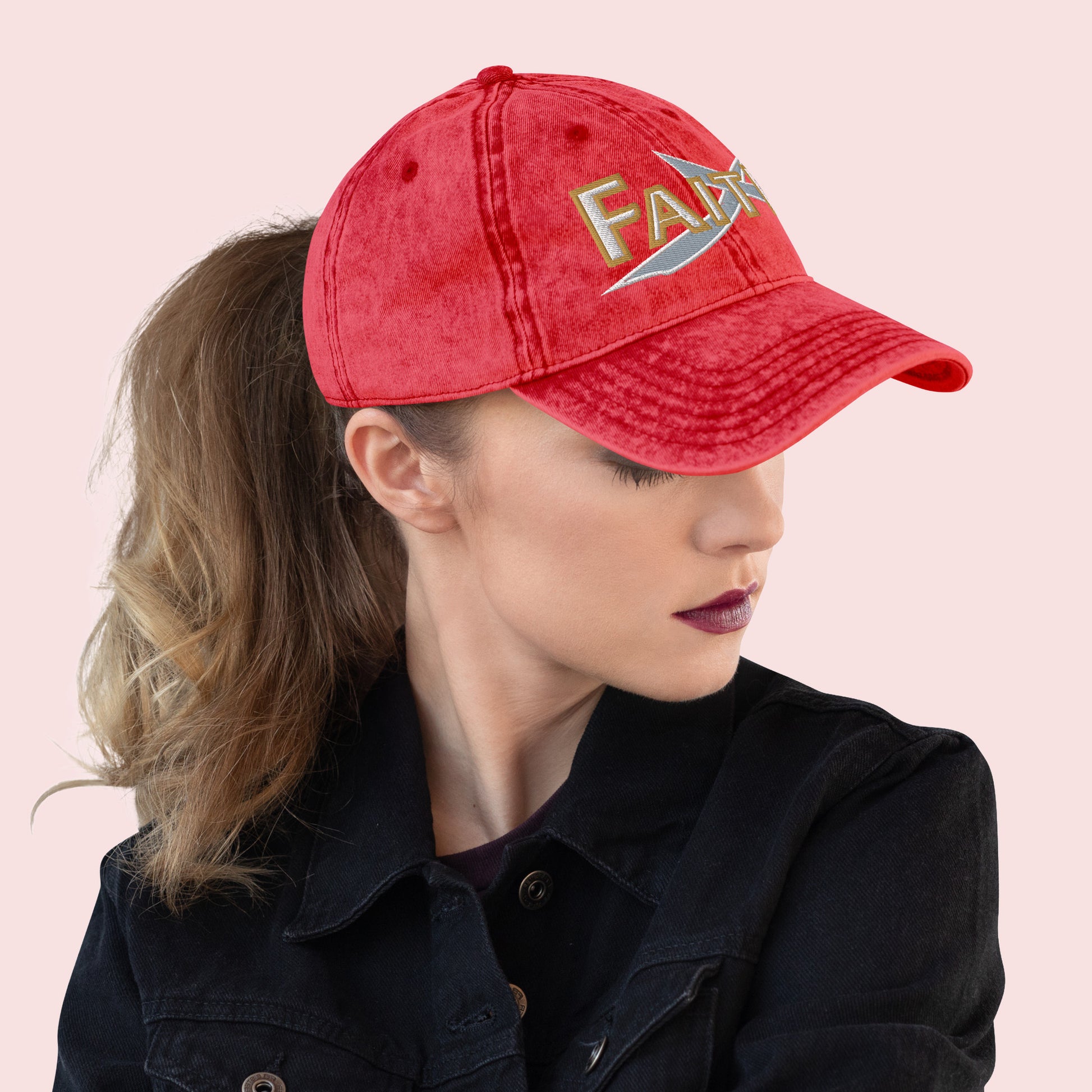 Side view of female wearing a red cap with 'FAITH' text on a light pink background