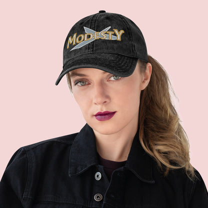 Female wearing a black cap with 'MODESTY' text on a pink background