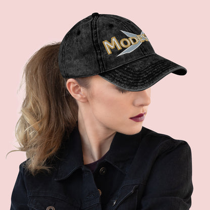 Side view of female wearing a black cap with 'MODESTY' text on a pink background