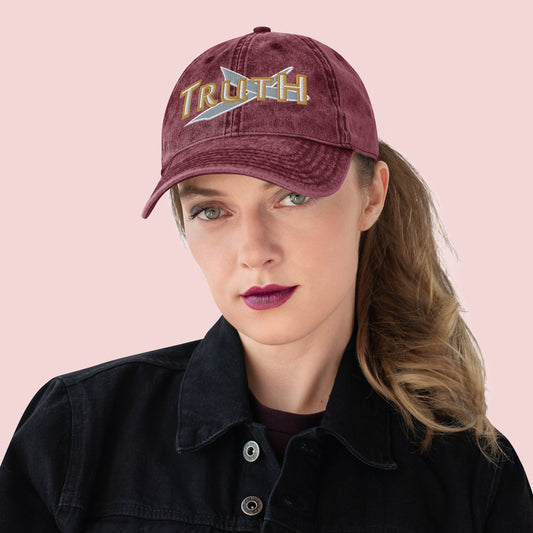 Person wearing a maroon cap with 'TRUTH' embroidery on a pink background