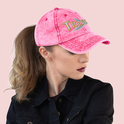 Female wearing a pink cap with 'TRUTH' branding on a pink background